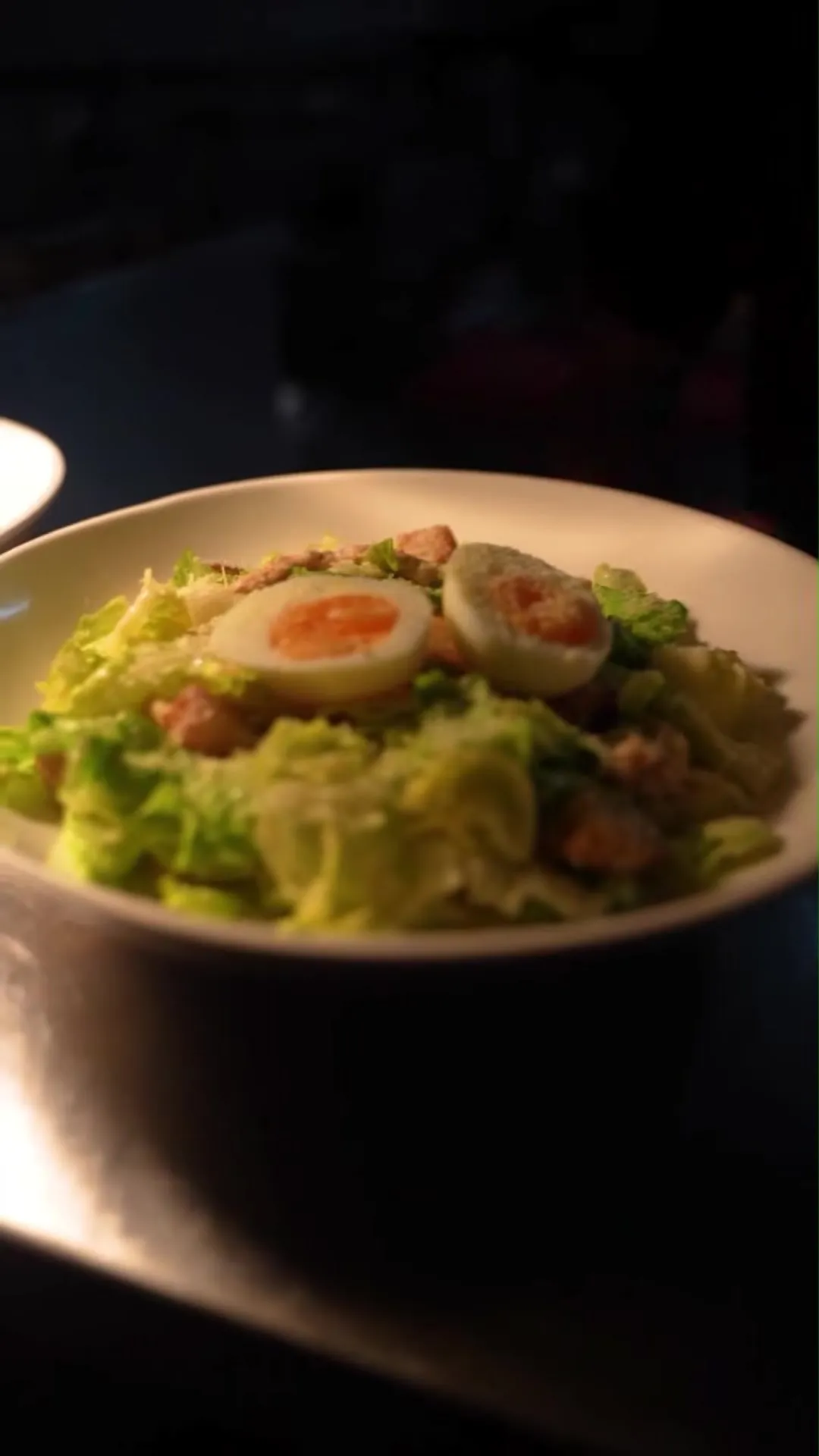 A Caesar salad with soft-boiled egg on the pass