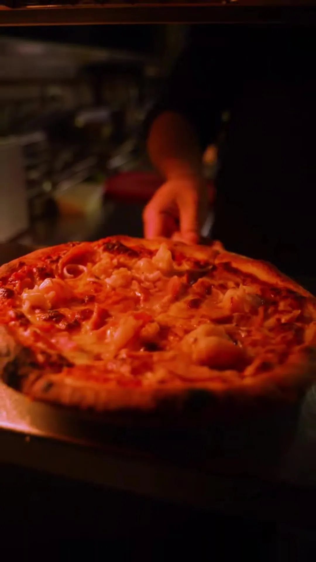 A Summer Island pizza with garlic prawns being set down on the pass