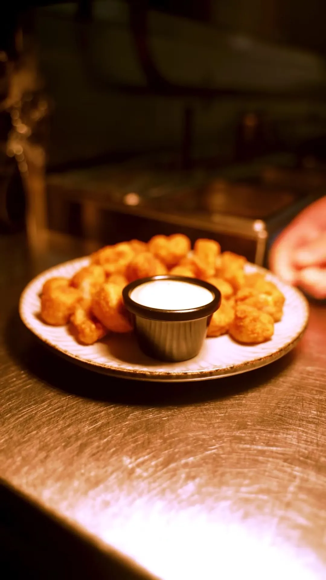 Popcorn chicken with jalapeño aioli set down on the steel pass under the heat lamp